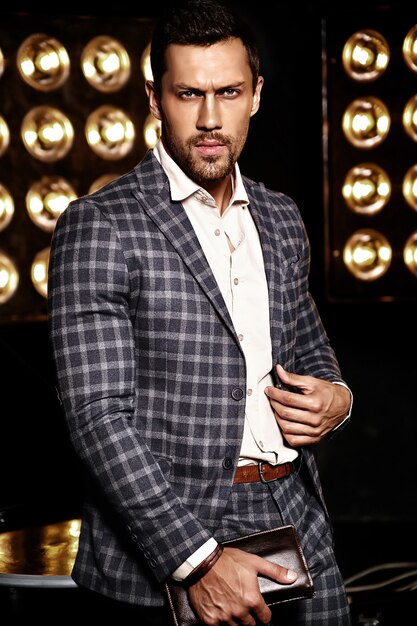 Retrato de hombre de modelo masculino de moda guapo sexy vestido con traje elegante sobre fondo negro de luces de estudio