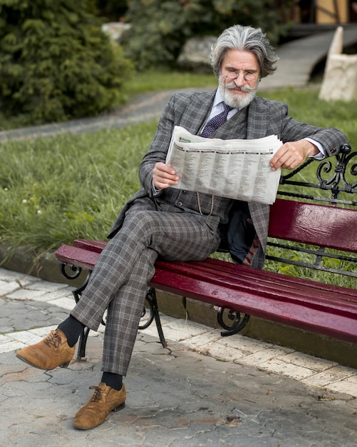 Foto gratuita retrato de hombre moderno leyendo el periódico en un banco