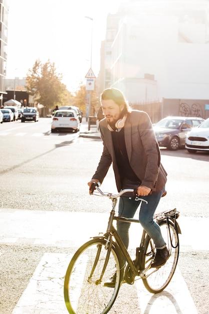 Retrato de un hombre montando bicicleta en el camino de la ciudad a la luz del sol