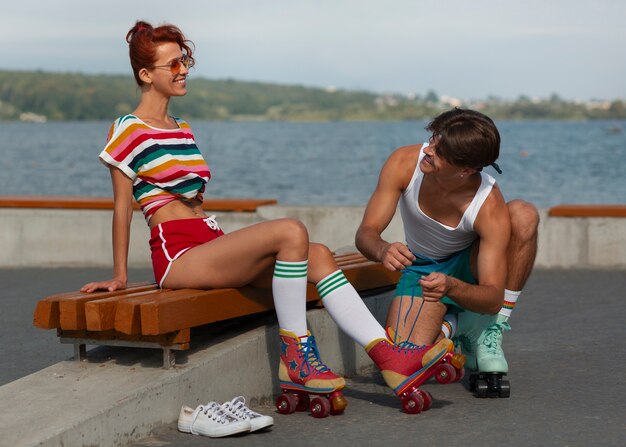 Retrato de hombre y mujer en la playa con patines en la estética de los 80