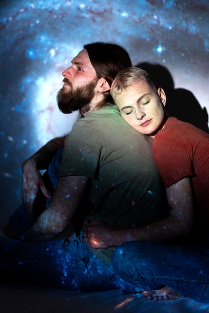 Retrato de hombre y mujer posando con textura de proyección del universo