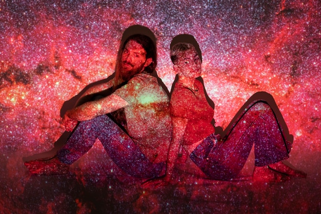 Foto gratuita retrato de hombre y mujer posando con textura de proyección del universo