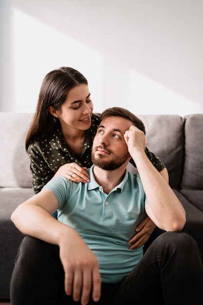 Retrato de hombre y mujer sonriendo el uno al otro en el sofá