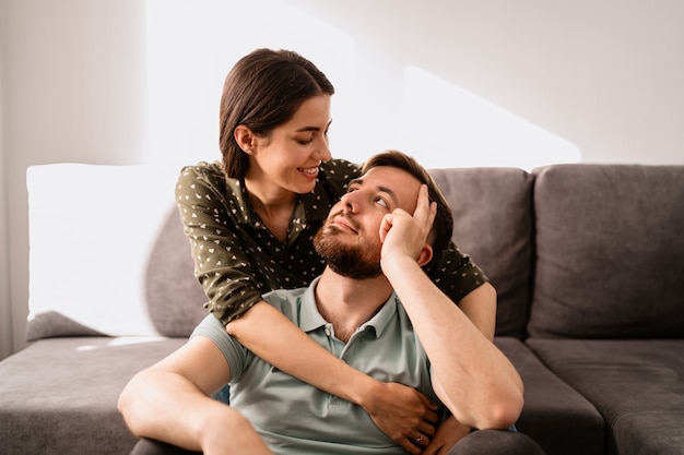 Retrato de hombre y mujer sonriendo el uno al otro en el sofá