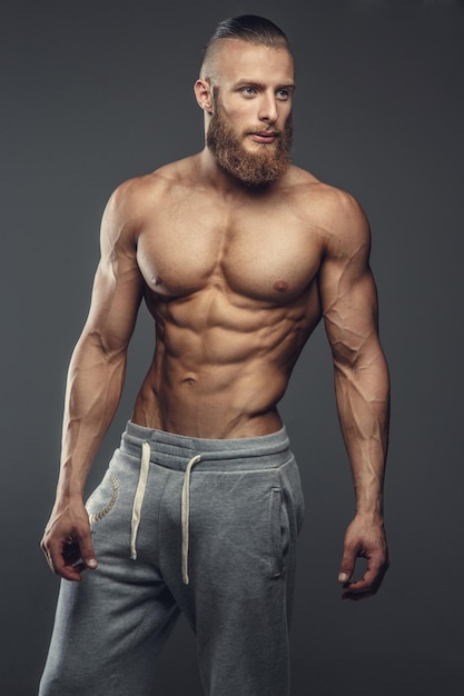 Retrato de hombre musculoso sin camisa con barba. Aislado sobre fondo gris.