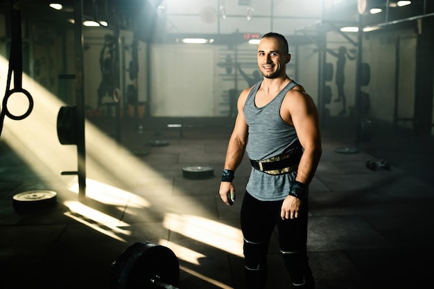 Retrato de un hombre musculoso feliz durante el entrenamiento con pesas en un club de salud