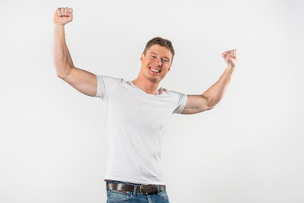 Retrato de un hombre musculoso sonriente apretando su puño contra el fondo blanco