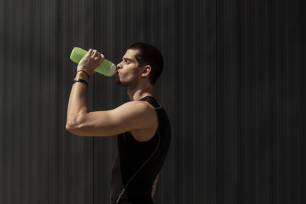 Retrato hombre musculoso tomando un descanso para hidratar su cuerpo después