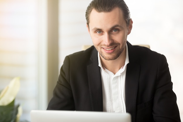 Foto gratuita el retrato del hombre de negocios acertado trabaja en la computadora portátil