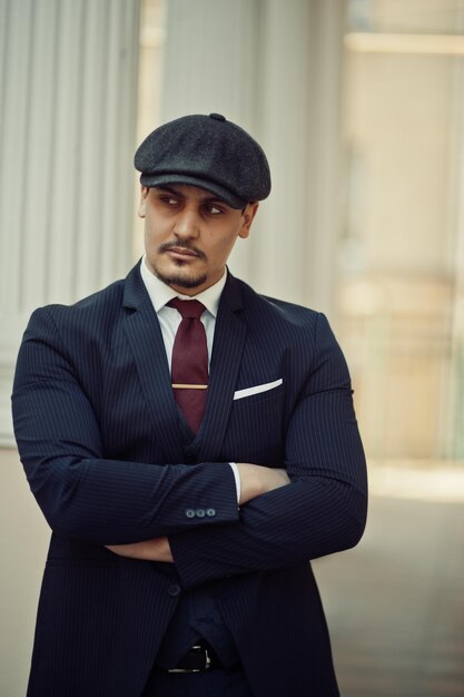 Retrato de un hombre de negocios árabe inglés retro de la década de 1920 con traje oscuro, corbata y gorra plana