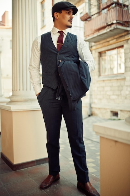 Foto gratuita retrato de un hombre de negocios árabe inglés retro de la década de 1920 con traje oscuro, corbata y gorra plana