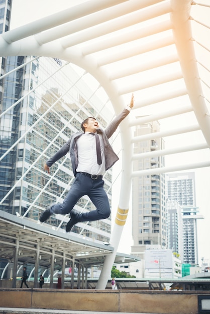 Retrato de hombre de negocios atractivo celebra por salto levanta su puño sobrecarga al aire libre.