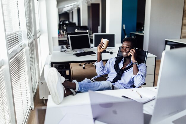 Retrato de hombre de negocios blanco trabajando en un proyecto en la oficina moderna, sosteniendo un café y relajándose.