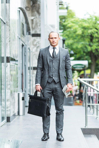 Foto gratuita retrato de un hombre de negocios con bolsa de ordenador portátil y periódico