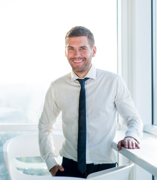 Retrato de un hombre de negocios feliz de pie en la oficina