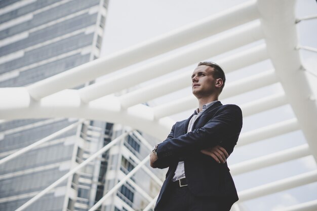 Retrato del hombre de negocios feliz que se coloca en frente del centro de negocios.