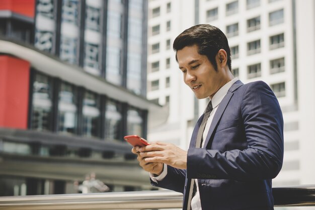 Retrato de hombre de negocios feliz usando teléfono al aire libre