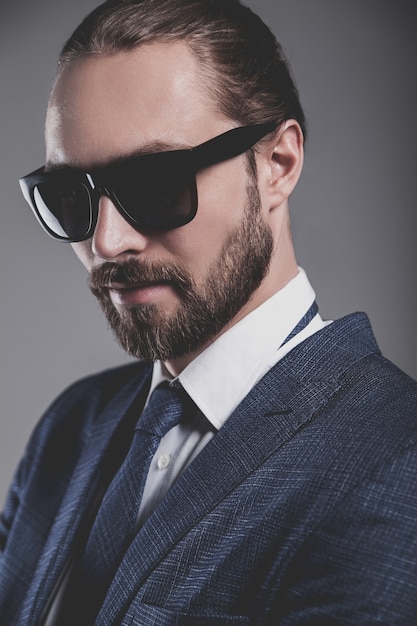 Retrato de hombre de negocios guapo modelo vestido con elegante traje azul con gafas de sol