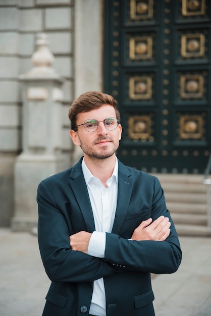 Retrato del hombre de negocios joven confiado con sus brazos cruzados