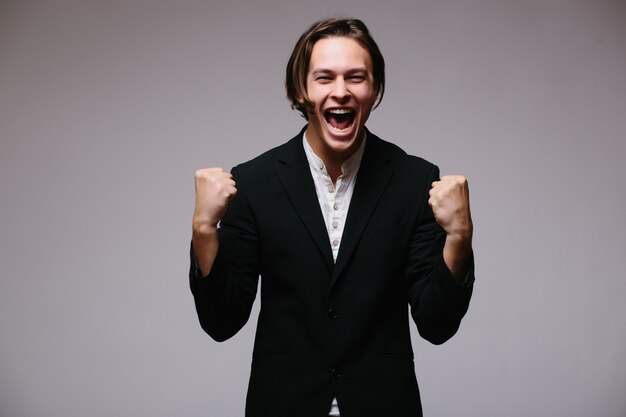 Retrato de un hombre de negocios joven enérgico disfrutando del éxito, gritando