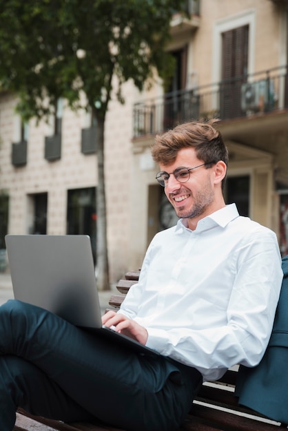 Retrato de un hombre de negocios joven sonriente que usa la computadora portátil