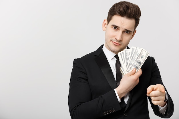 Retrato de hombre de negocios mostrando dinero y señalando con el dedo aislado sobre fondo blanco.