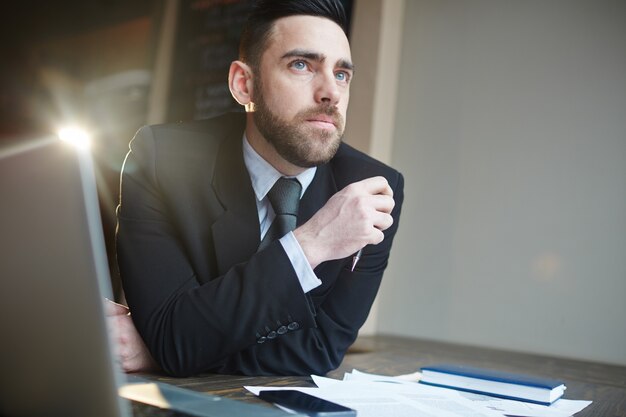 Retrato de hombre de negocios pensando en el escritorio