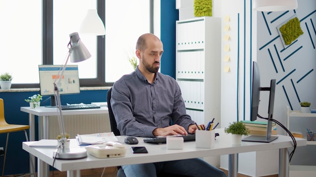 Retrato de un hombre de negocios que trabaja con una computadora en una estrategia de crecimiento, creando un análisis financiero con tablas y gráficos. Presentación de datos ejecutivos de planificación de empleados masculinos en el escritorio.