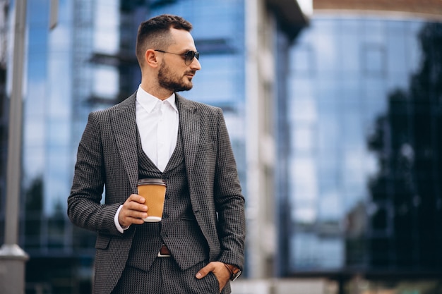 Retrato de hombre de negocios por el rascacielos tomando café