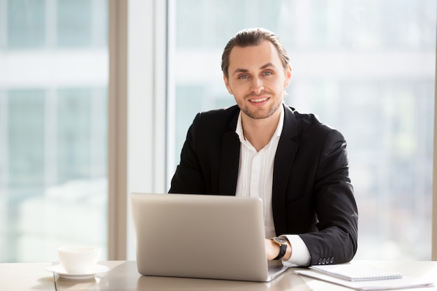 Retrato del hombre de negocios sonriente hermoso en el trabajo en oficina.