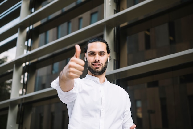 Foto gratuita retrato de un hombre de negocios sonriente que muestra el pulgar encima de la muestra