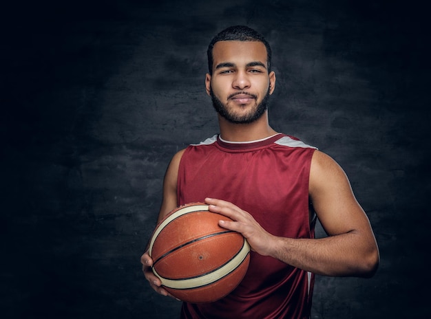 Retrato de un hombre negro barbudo sostiene una pelota de baloncesto.