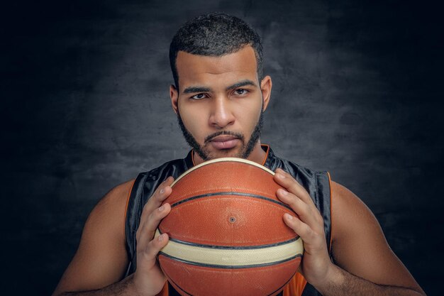 Retrato de un hombre negro barbudo sostiene una pelota de baloncesto.