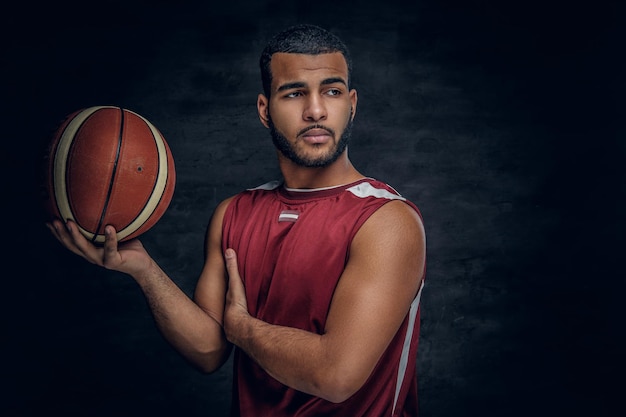 Retrato de un hombre negro barbudo sostiene una pelota de baloncesto.