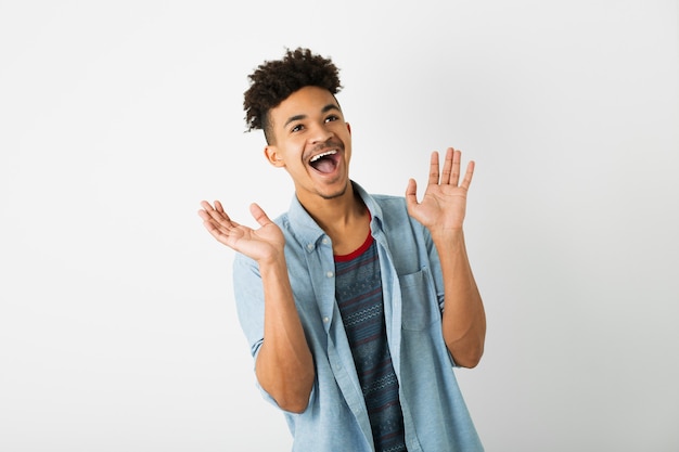 Retrato de hombre negro joven inconformista posando sobre fondo de pared de estudio blanco aislado, traje elegante, peinado afro divertido, expresión de la cara sonriente, feliz, sorprendida, sorprendida, divertida