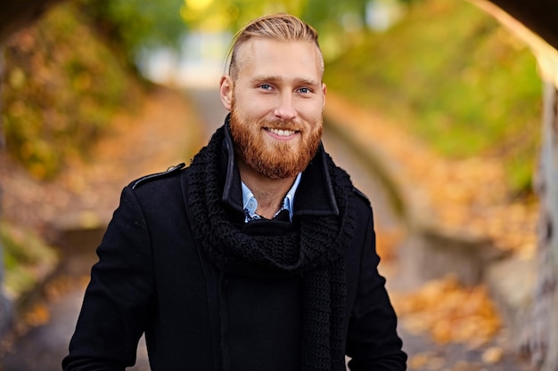 Retrato de hombre pelirrojo sonriente en un parque de otoño.