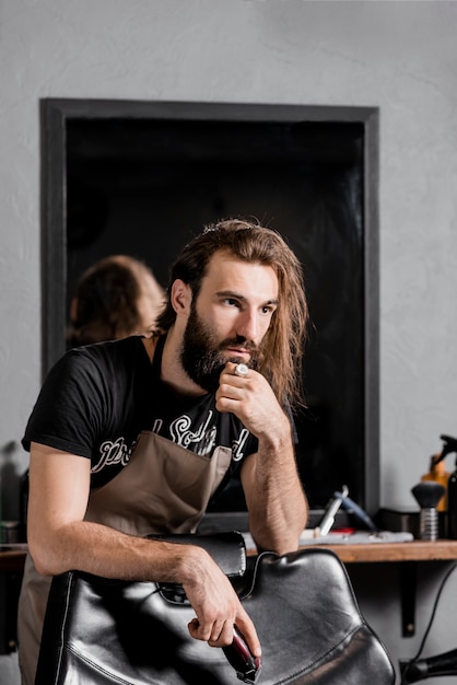 Retrato de un hombre peluquero con trimmer eléctrico