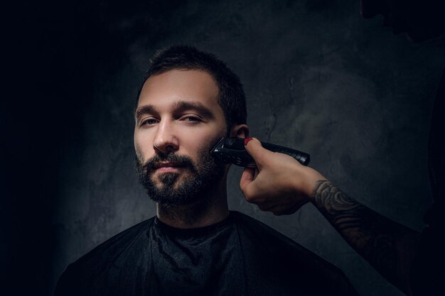 Retrato de un hombre pensativo con bigote y procedimiento de recorte de barba en la barbería.