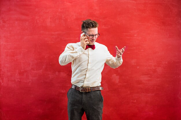 Retrato de hombre perplejo hablando por teléfono un rojo