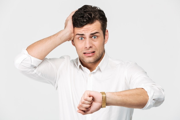 Foto gratuita retrato de un hombre preocupado perplejo mostrando su reloj de pulsera