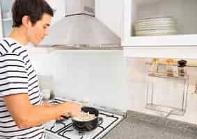 Foto gratuita retrato del hombre que fríe palomitas de maíz en cacerola de la salsa en la cocina