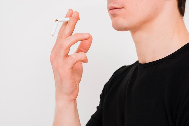 Retrato del hombre que sostiene el cigarrillo roto en la pared blanca