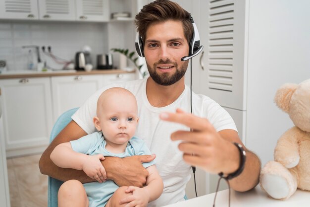 Foto gratuita retrato de hombre que trabaja mientras sostiene al bebé