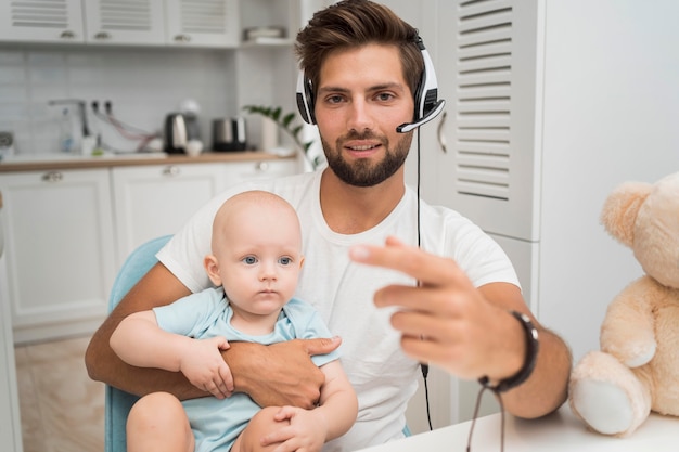 Retrato de hombre que trabaja mientras sostiene al bebé