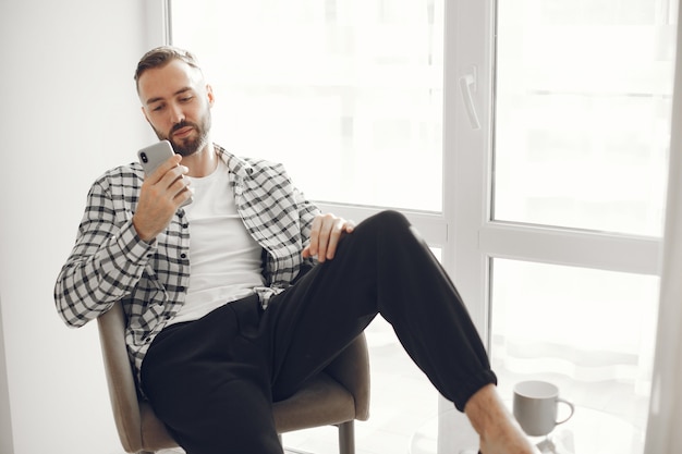 Retrato de hombre relajado en casa con smartphone