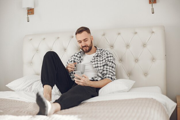 Retrato de hombre relajado en casa con smartphone