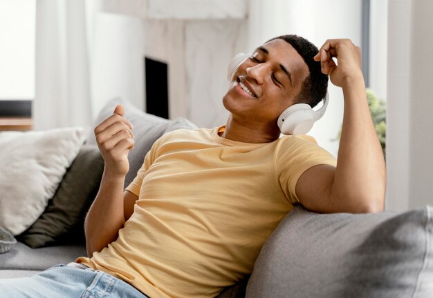 Retrato de hombre relajándose en casa mientras escucha música