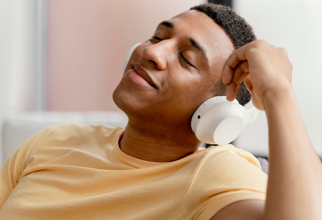 Retrato de hombre relajándose en casa mientras escucha música