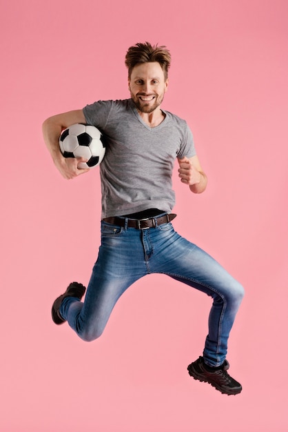 Retrato, hombre, saltar, tenencia, pelota del fútbol