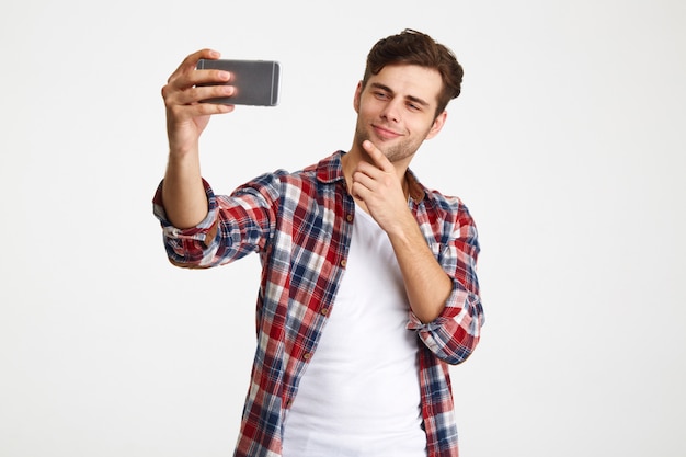 Retrato de un hombre satisfecho tomando una selfie mientras está de pie